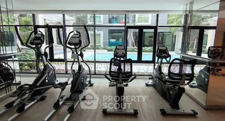 Modern gym with exercise equipment overlooking a pool, offering a luxurious fitness experience.