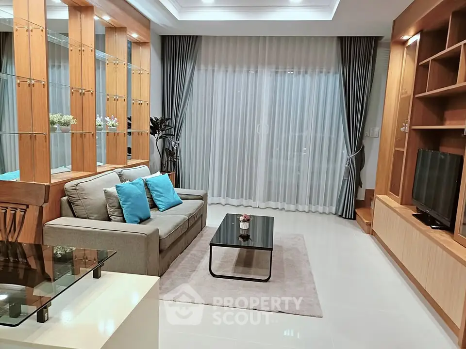 Elegant living room with modern decor and large window, featuring cozy seating and stylish shelving.