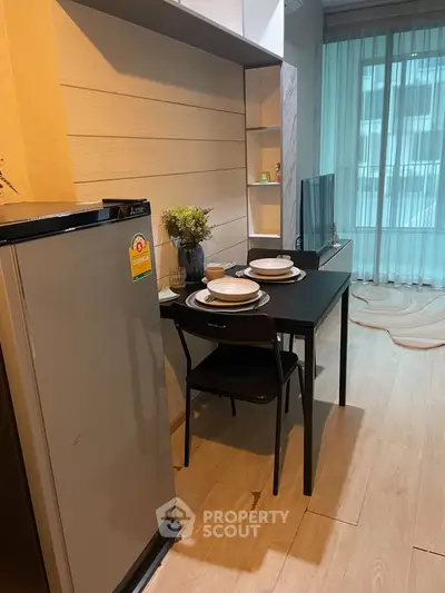 Modern dining area with sleek table and chairs, adjacent to a compact kitchen and large window view.