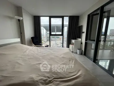 Modern bedroom with large windows offering city views and minimalist decor.