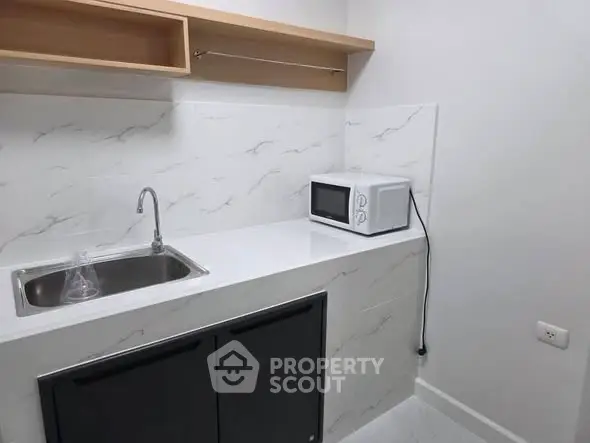 Compact kitchen with modern sink and microwave, ideal for small spaces.