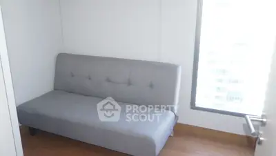 Cozy minimalist room with a modern gray sofa and large window offering natural light.