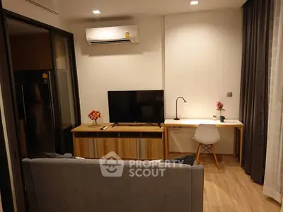 Modern living room with TV, desk, and air conditioning in cozy apartment.