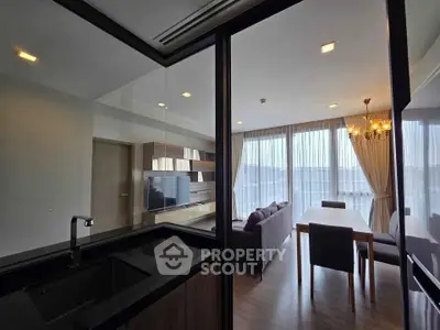 Modern living room with elegant dining area and large windows offering natural light.