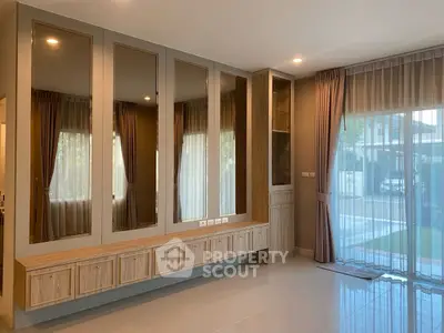 Spacious modern living room with large windows and elegant wooden cabinetry.