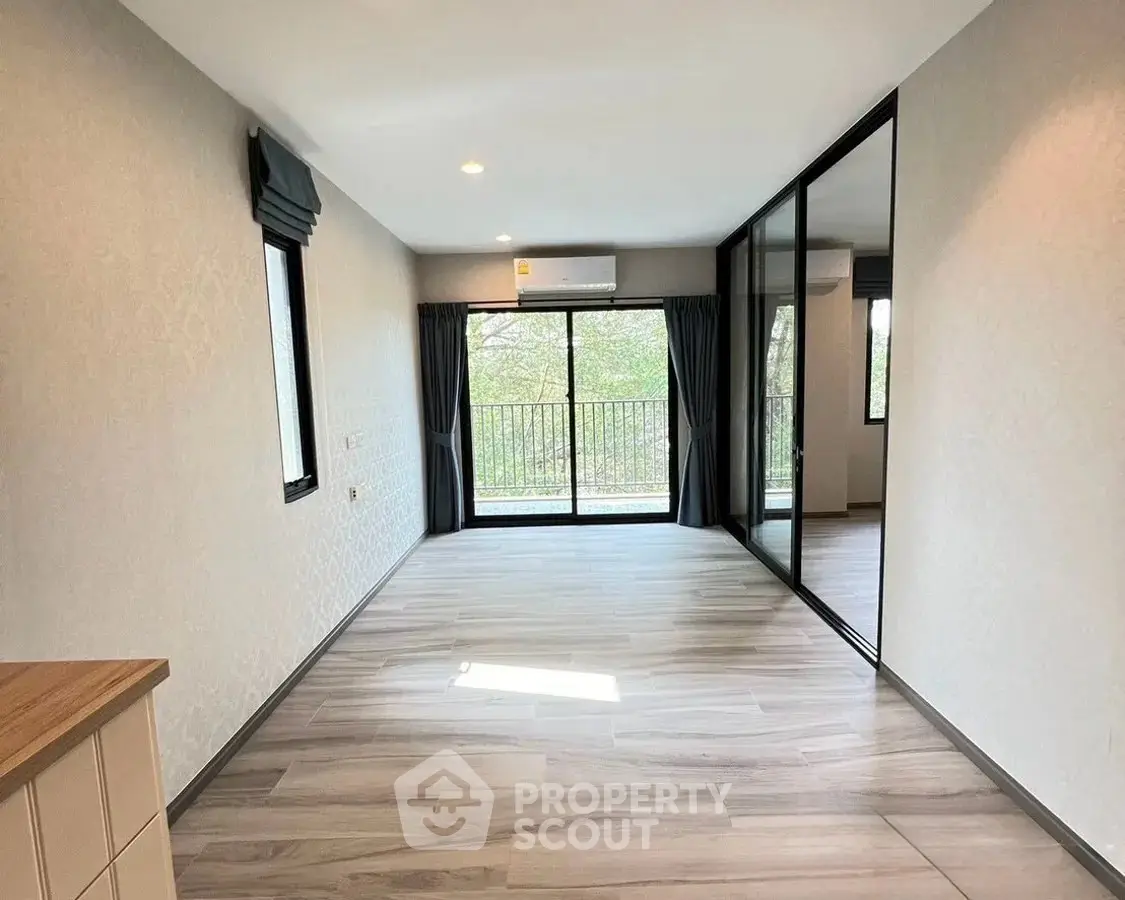 Spacious modern living room with large windows and balcony access, featuring elegant flooring and neutral decor.