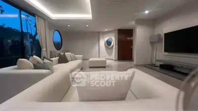 Luxurious modern living room with elegant white sofas and large windows offering serene views.