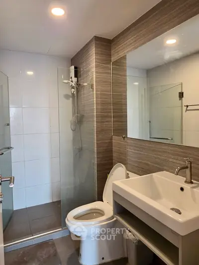 Modern bathroom with glass shower and sleek fixtures in contemporary apartment.