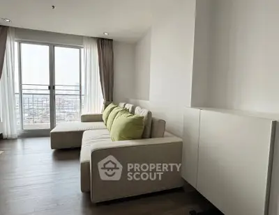 Modern living room with large windows and city view, featuring a cozy sofa and stylish decor.