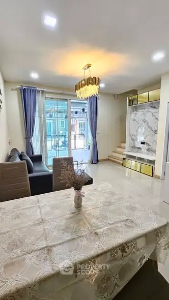 Elegant living room with modern decor, plush sofa, and stylish chandelier, perfect for cozy gatherings.