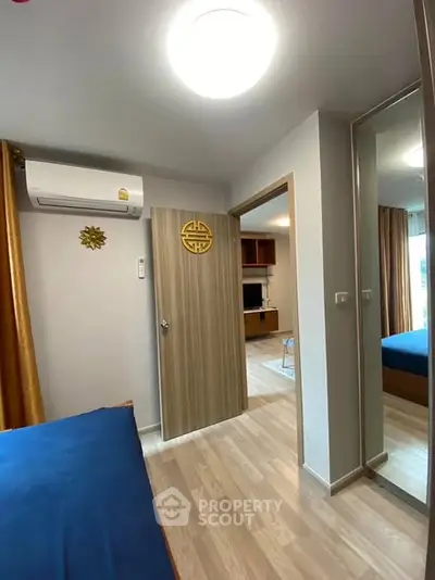 Modern bedroom with air conditioning and wooden flooring, featuring a mirrored wardrobe.
