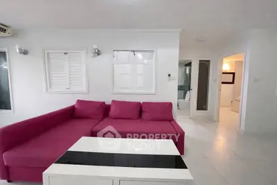 Modern living room with vibrant pink sofa and sleek white decor