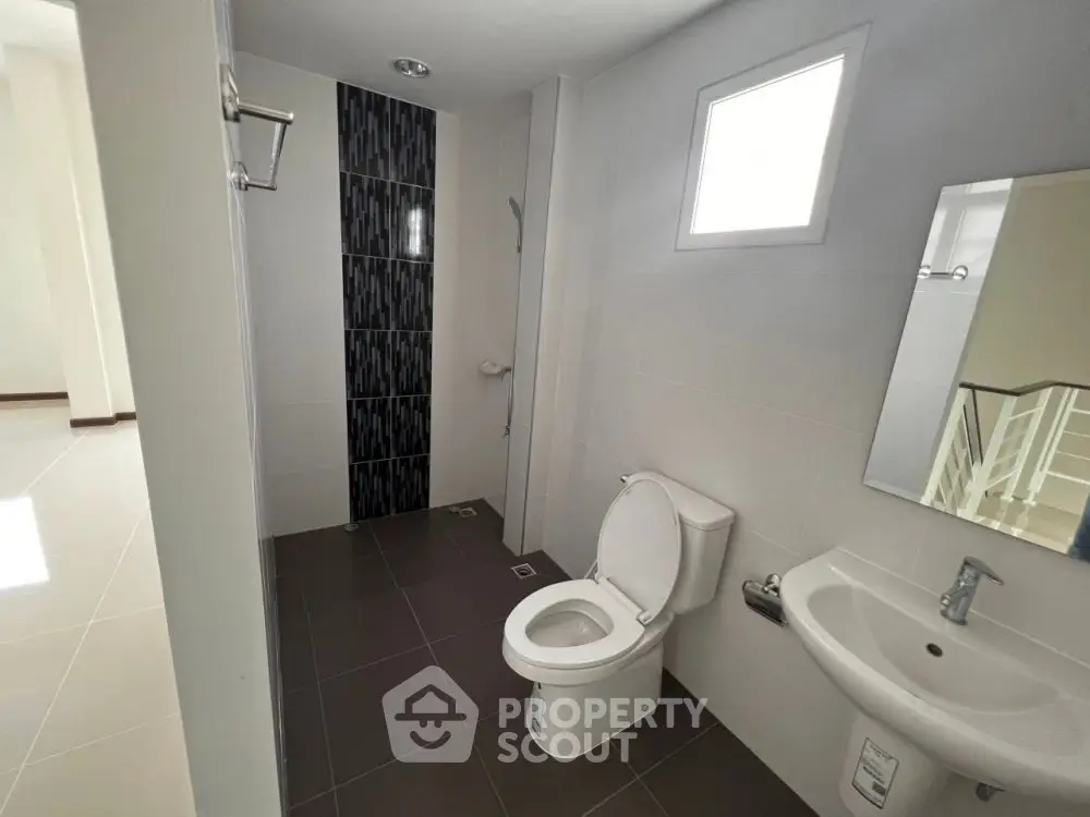 Modern bathroom with sleek design, featuring a toilet, sink, and shower area with stylish tiles.