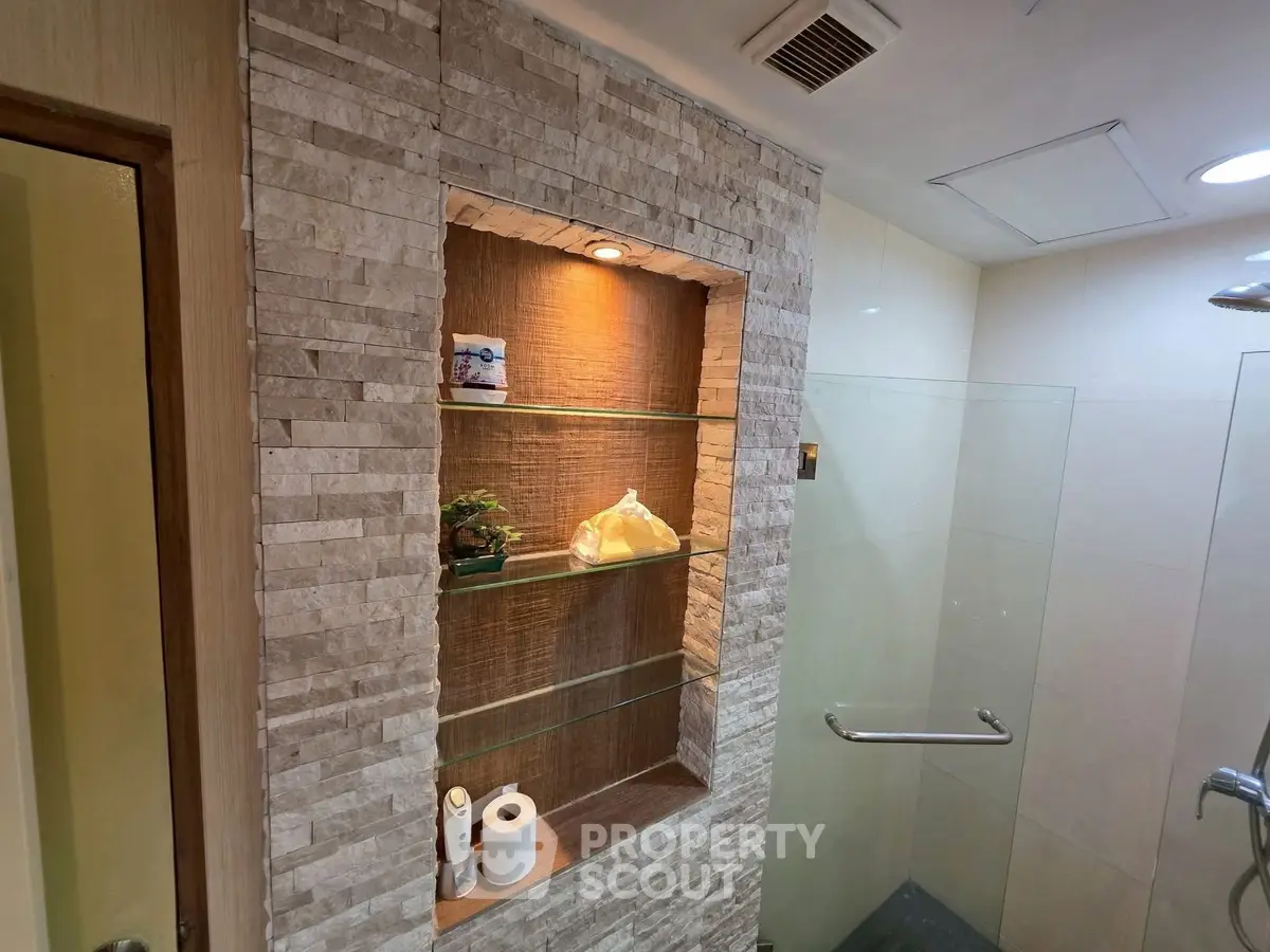 Modern bathroom with stone accent wall and glass shelves