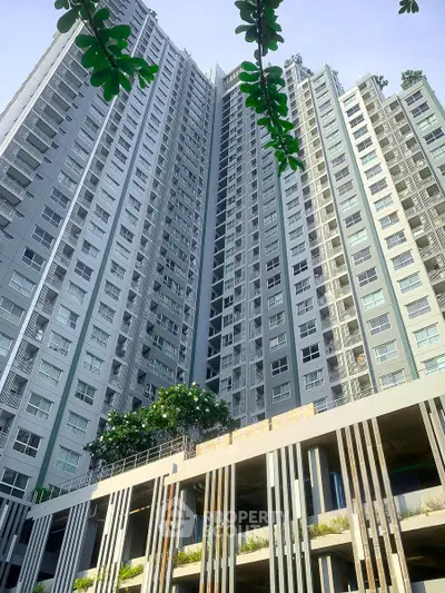 Modern high-rise residential building with lush greenery and sleek architectural design.