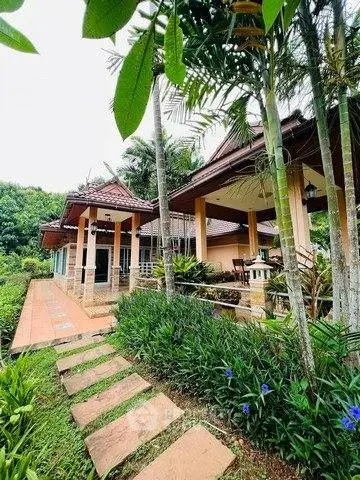 Charming tropical villa with lush garden and inviting outdoor patio, perfect for serene living.