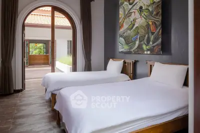 Spacious bedroom with twin beds and elegant decor, featuring a large window with a view of the terrace.