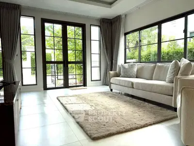 Spacious living room with large windows and cozy seating, perfect for relaxation and natural light.