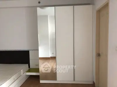 Spacious bedroom with modern wardrobe and wooden flooring in a stylish apartment.