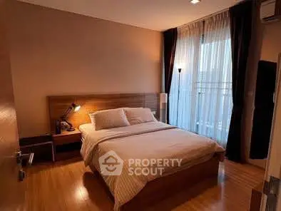 Cozy bedroom with wooden flooring and large window for natural light