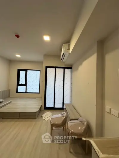 Modern minimalist bedroom with large windows and air conditioning, featuring sleek furniture and neutral tones.