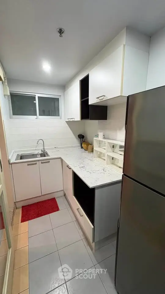 Modern kitchen with sleek cabinetry and stainless steel fridge in compact layout.