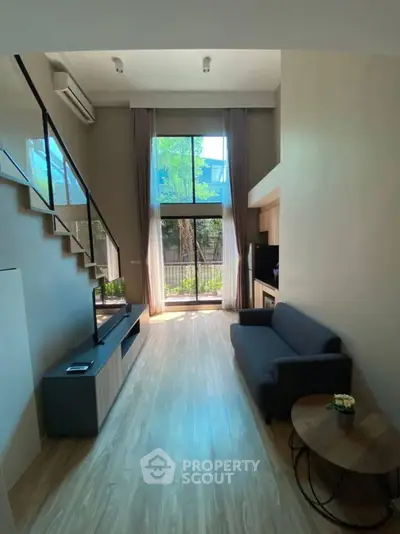 Modern loft-style living room with high ceilings and large windows.