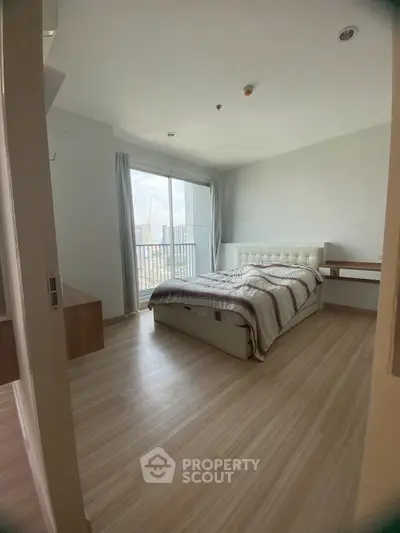 Spacious bedroom with modern decor and balcony view in a high-rise apartment.