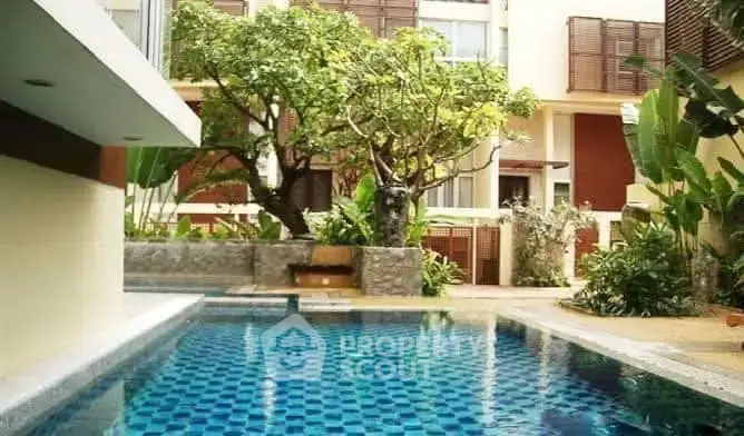 Luxurious residential pool area with lush greenery and modern architecture.