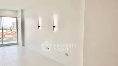 Spacious minimalist living room with modern wall lights and large windows offering city views.