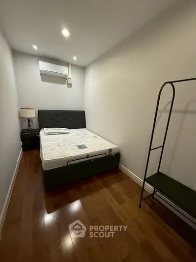 Cozy bedroom with wooden flooring and modern furnishings, perfect for a comfortable living experience.