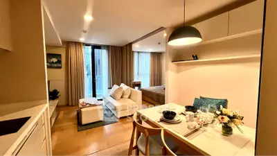 Modern open-plan living room with dining area and cozy bedroom in stylish apartment.