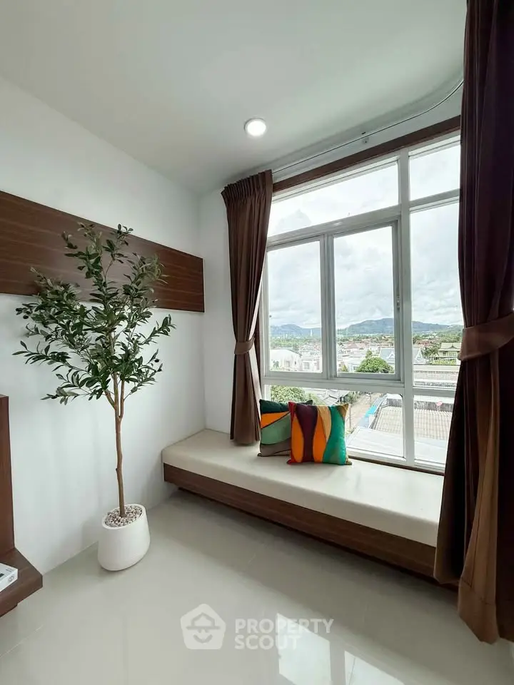 Bright corner unit with large window and scenic view, featuring cozy seating and modern decor.