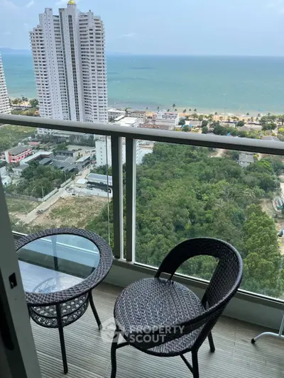 Stunning high-rise balcony with ocean view and cozy seating area.