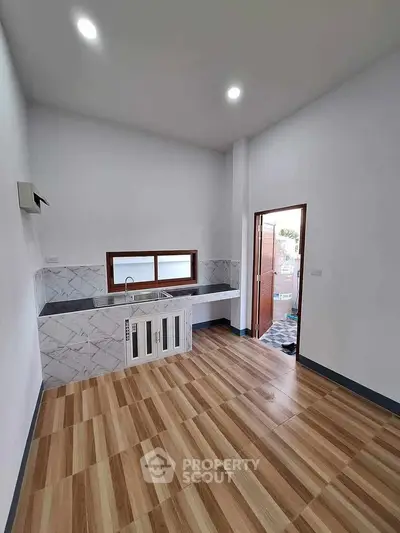 Modern kitchen with sleek design and wooden flooring, featuring ample natural light.