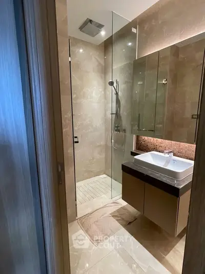Luxurious modern bathroom with glass shower and elegant vanity in upscale apartment.