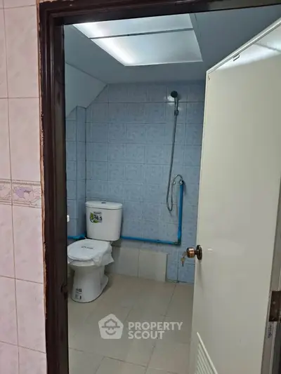 Compact bathroom with shower and toilet, featuring blue tiled walls and simple design.