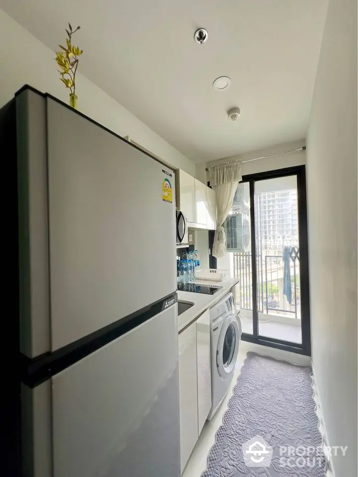 Modern kitchen with washing machine and balcony view in urban apartment