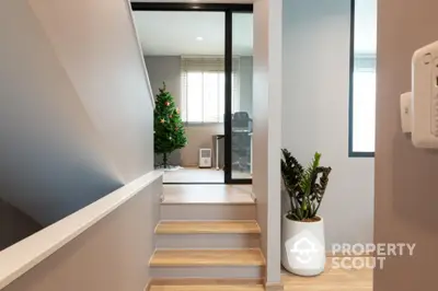 Modern interior with staircase and Christmas tree, featuring stylish decor and natural light.