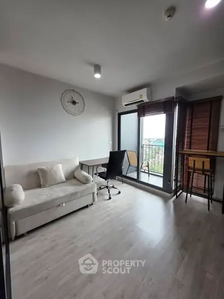 Modern living room with balcony view, featuring sleek furniture and abundant natural light.