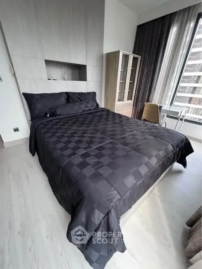 Modern bedroom with sleek black bedding and large window for natural light