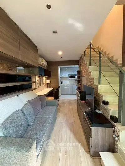Modern living room with stylish staircase and open kitchen layout in urban apartment.