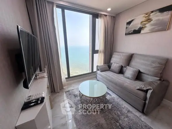 Modern living room with stunning ocean view, featuring sleek furniture and large windows.