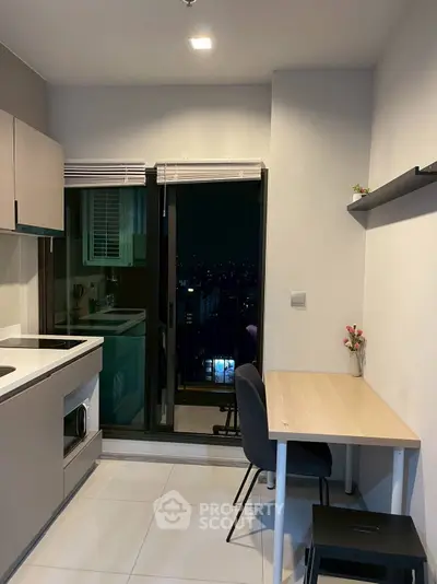 Modern compact kitchen with balcony view, featuring sleek cabinetry and cozy dining area.