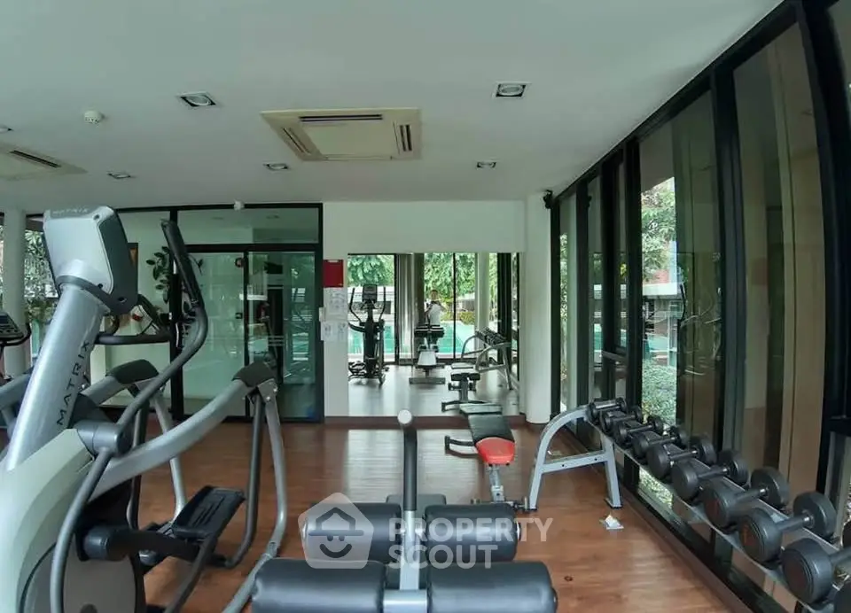 Modern gym with large windows and fitness equipment in a residential building.