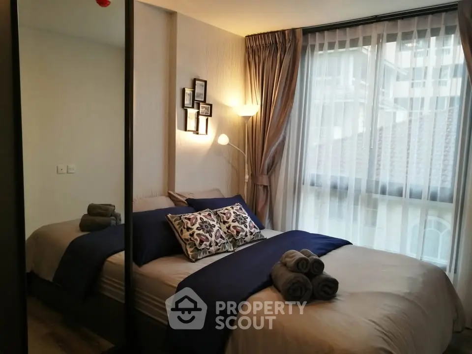 Cozy bedroom with modern decor and large window offering natural light.