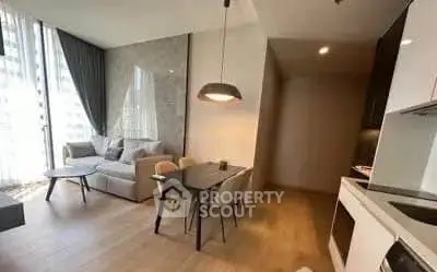 Modern living room with open kitchen, stylish decor, and natural light.