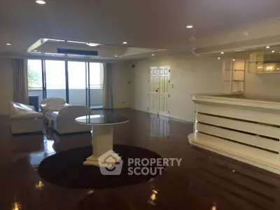 Spacious open-plan living room with elegant furniture and polished wooden floors.