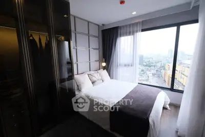 Modern bedroom with large window offering city view, featuring sleek wardrobe and cozy bedding.