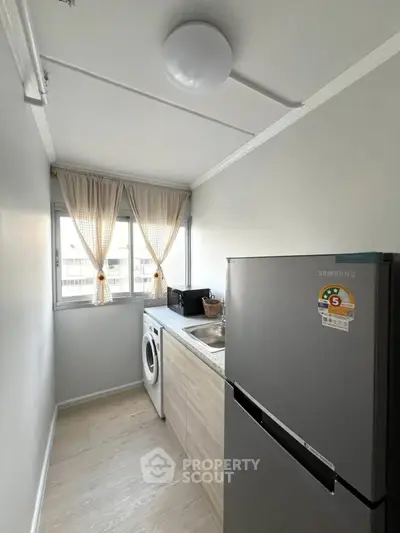 Compact kitchen with washing machine and fridge in modern apartment